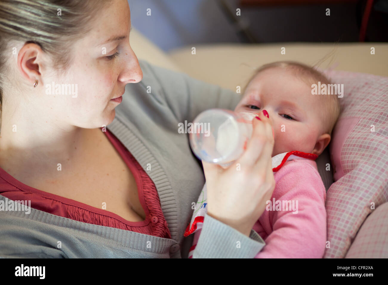 Mother feeding infant girl with baby formula Stock Photo