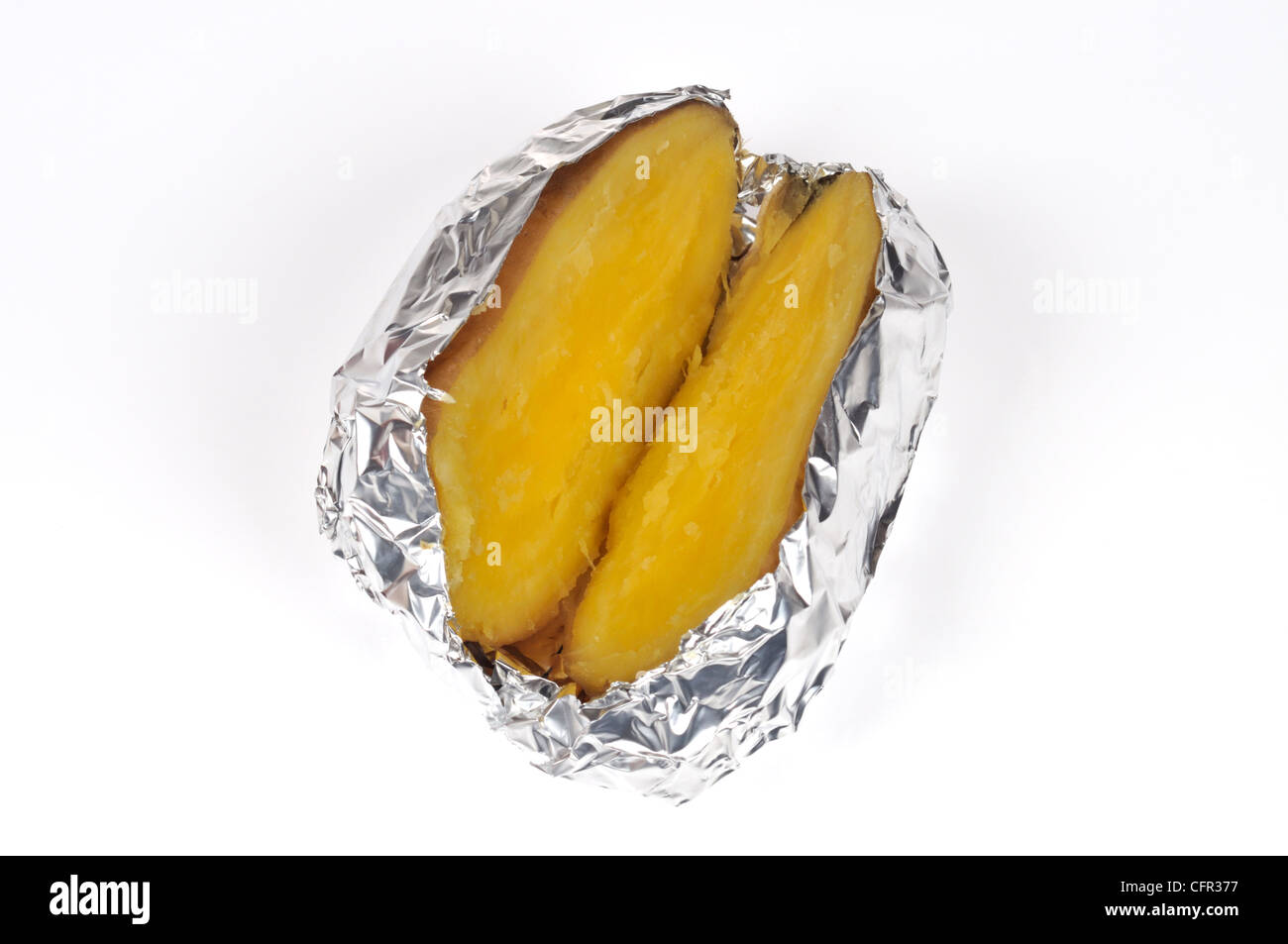 Cooked baked jacket yukon gold potato cut in half wrapped in tin foil on white background cut out Stock Photo