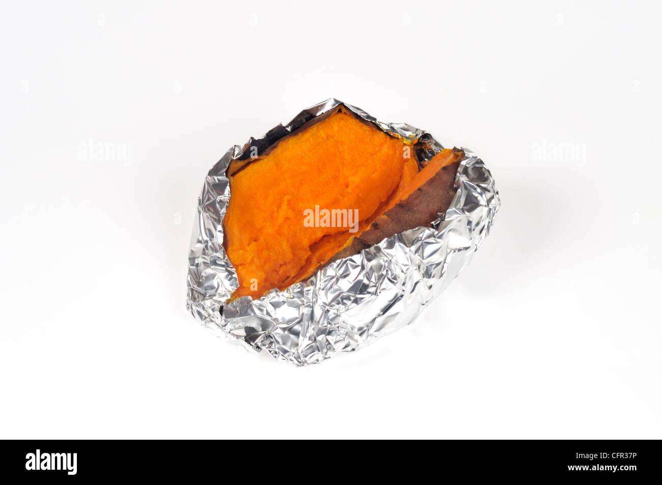 Yam also known as a sweet potato in USA cooked in tin foil and cut in half on white background cut out. Stock Photo