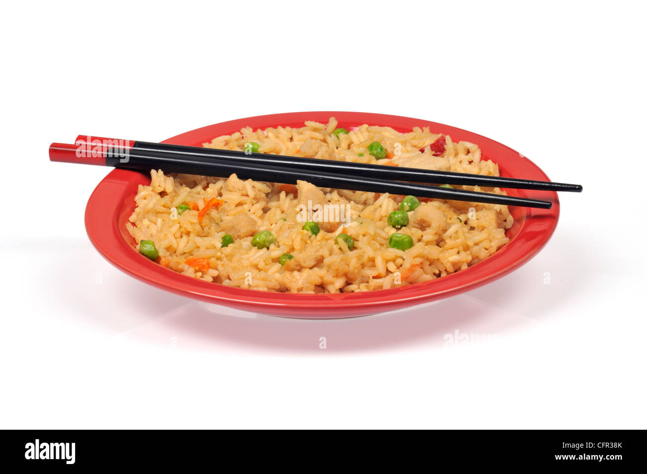 Oriental chicken fried rice with vegetables and chopsticks isolated on red plate Stock Photo