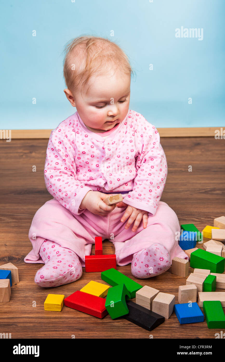 Infant child playing with bricks on wooden floor Stock Photo