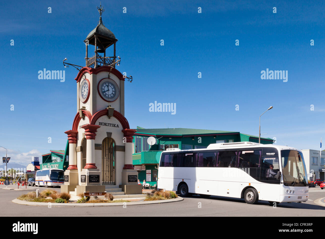 Tourist coach rounding the ornate clock tower in the centre of Hokitika Stock Photo