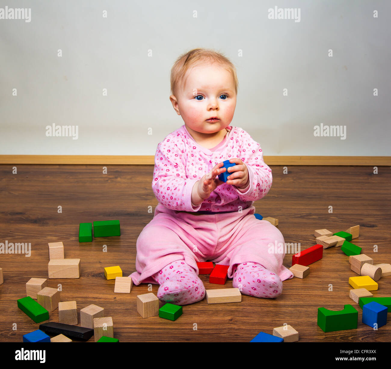 Infant child playing with bricks on wooden floor Stock Photo