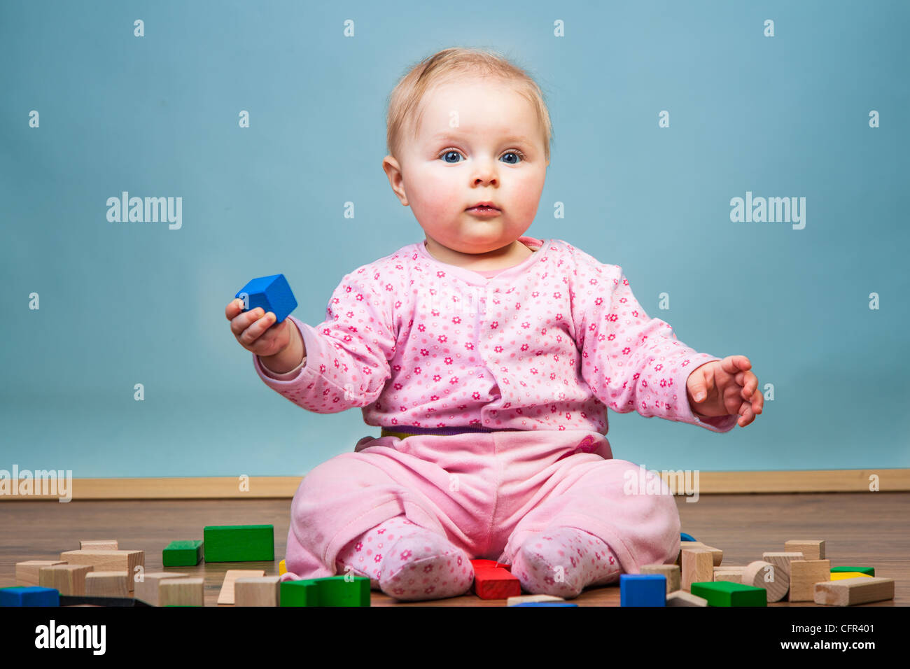 Infant child playing with bricks on wooden floor Stock Photo