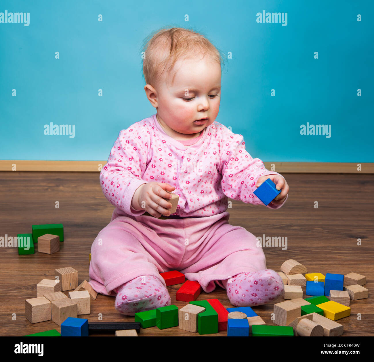 Infant child playing with bricks on wooden floor Stock Photo