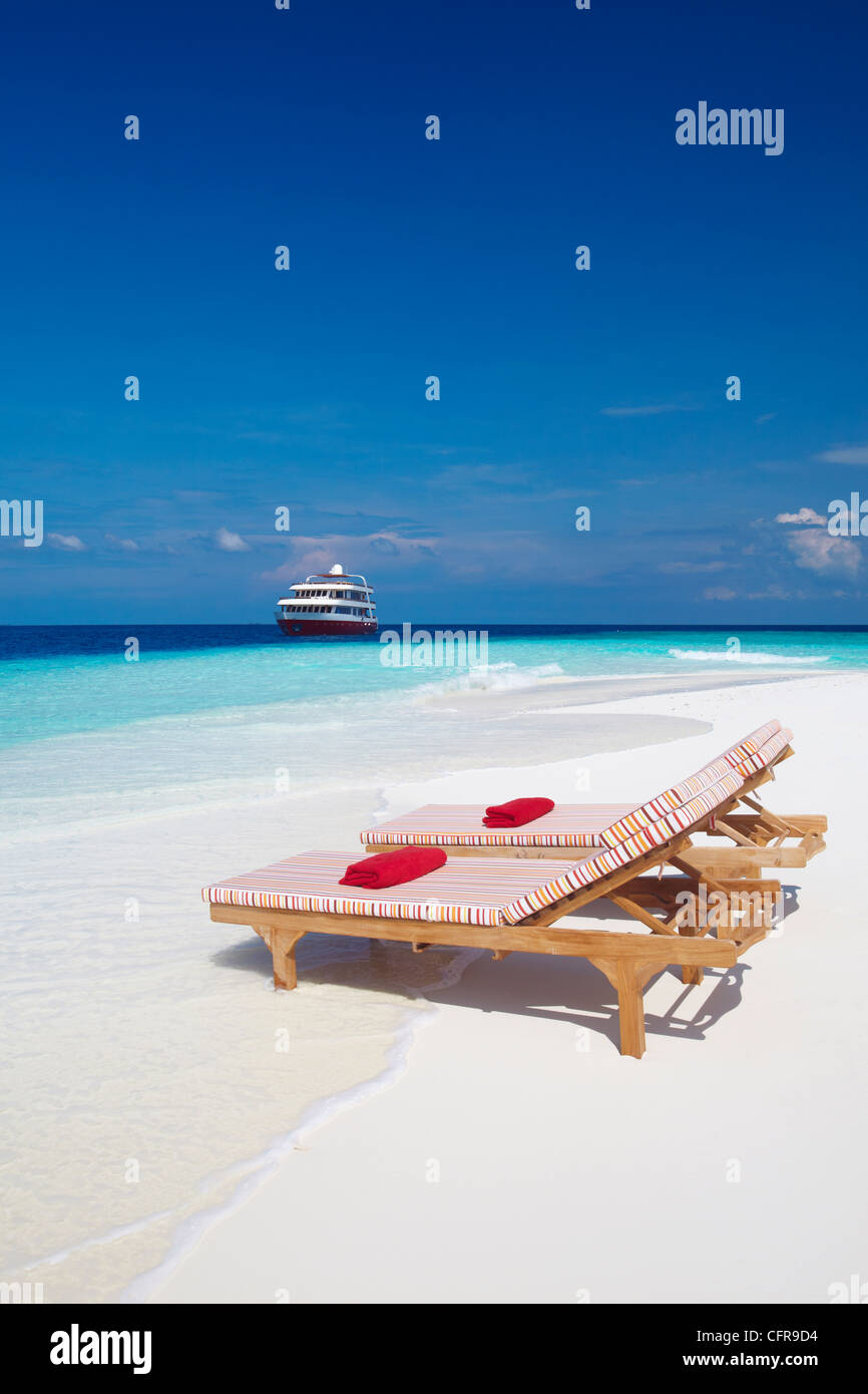 Lounge chairs on beach and yacht, Maldives, Indian Ocean, Asia Stock Photo