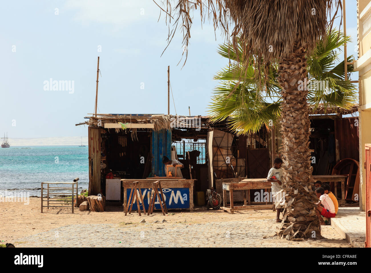 Sal Rei, Boa Vista, Cape Verde Islands, Africa. Furniture workshop in a wooden shack below a palm tree on the city waterfront Stock Photo
