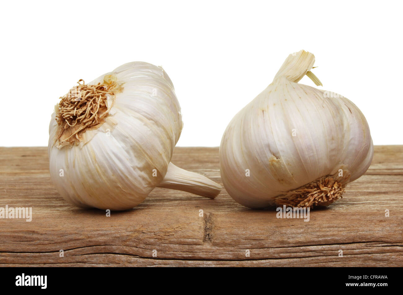 Two garlic bulbs on old weathered wood against a white background Stock Photo