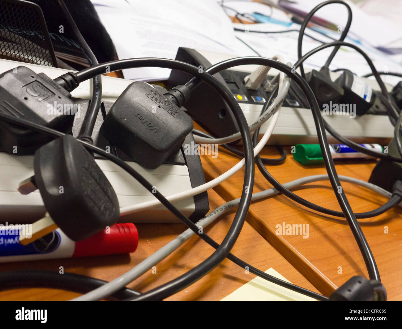 Tangle of computer wires, cables and plugs on an untidy office desk. Stock Photo