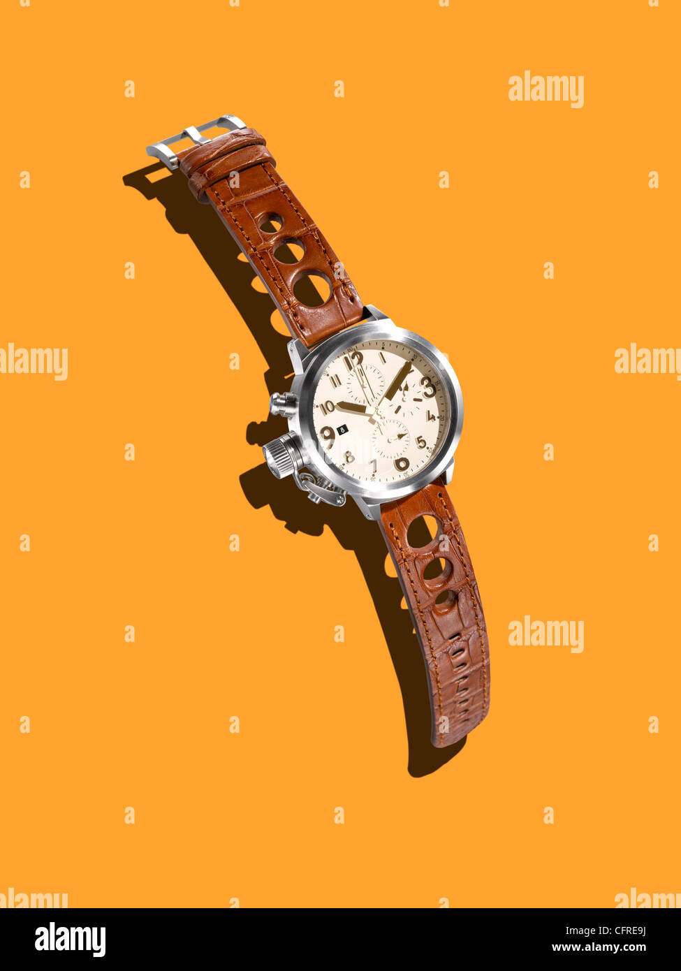 A modern watch with a leather strap on a mustard background with creative shadow. Stock Photo