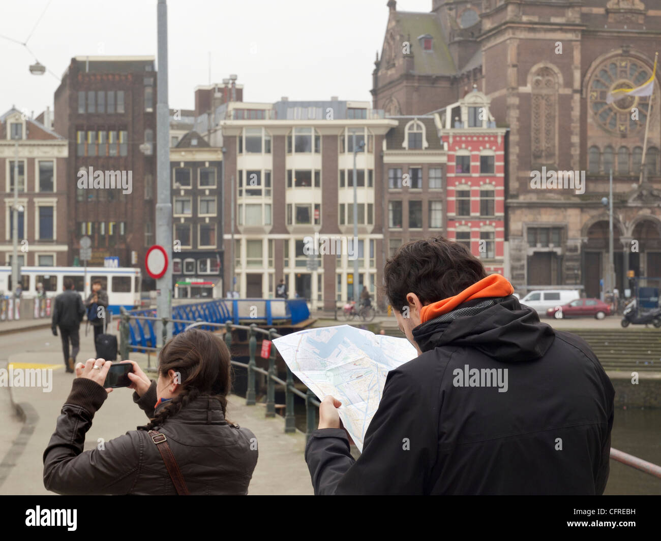 Tourist couple with woman taking digital photo and man looking at map, in Amsterdam, the Netherlands Stock Photo