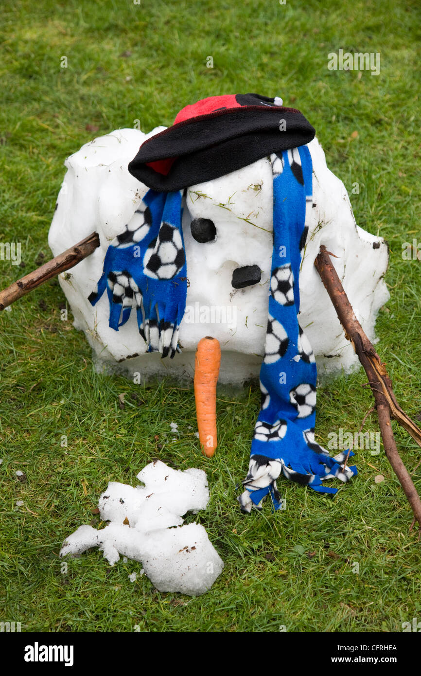 Melted and melting snowman thawing out with carrot nose, stick arms and