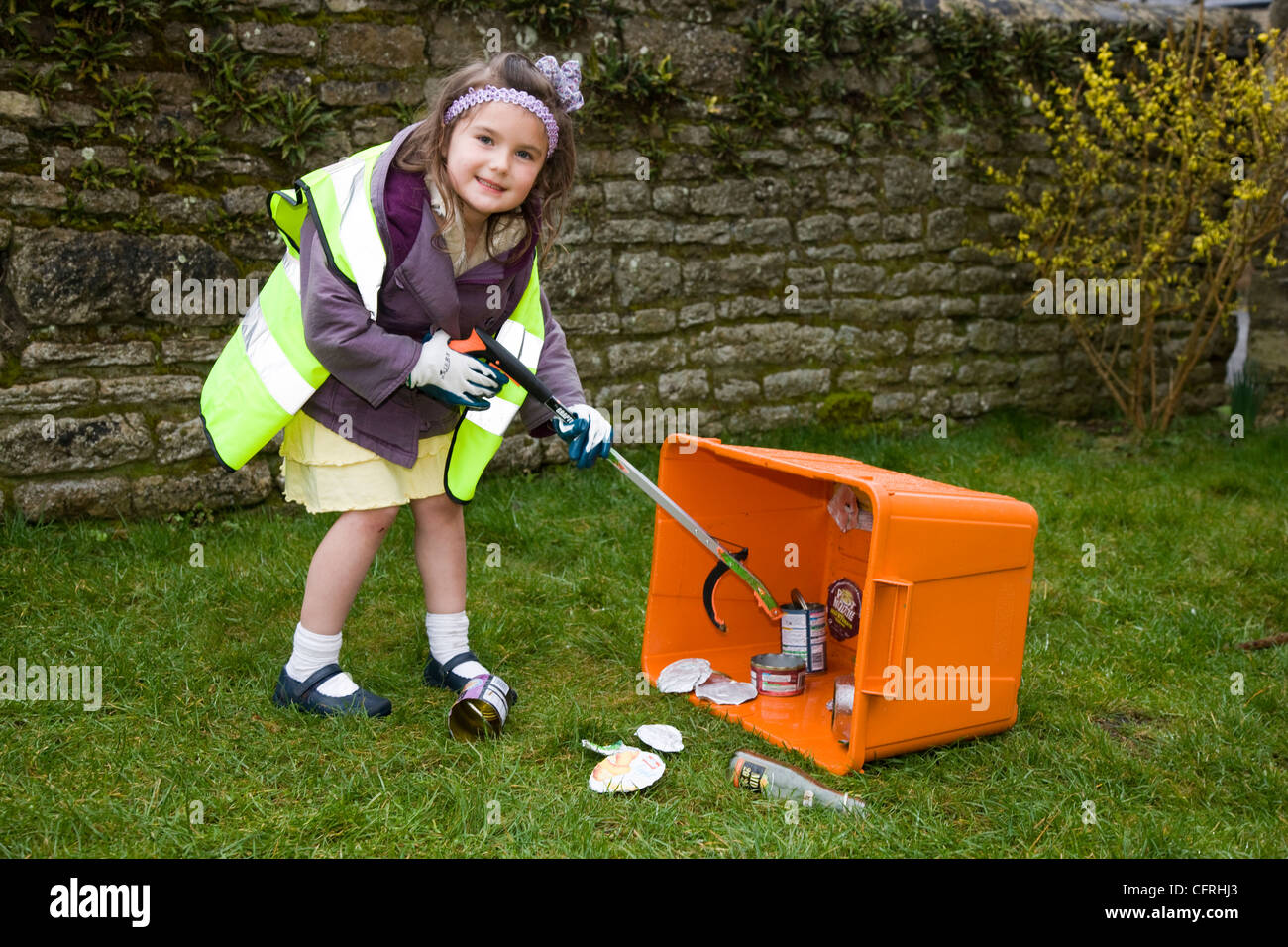 Young girl with litter picker, picking up litter into a recycling box