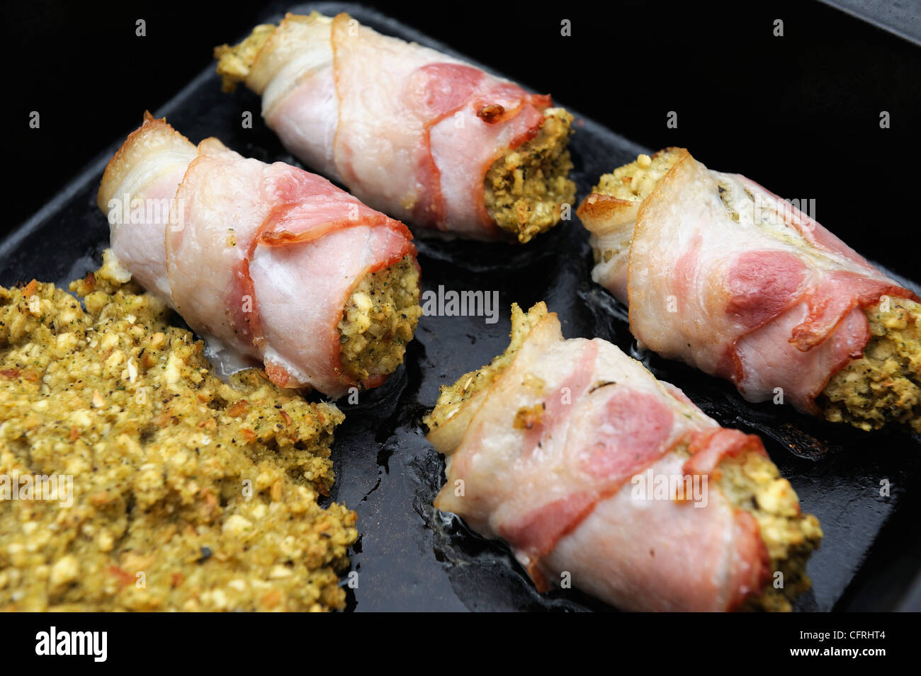 bacon and stuffing rolls cooking in an over pan england uk Stock Photo
