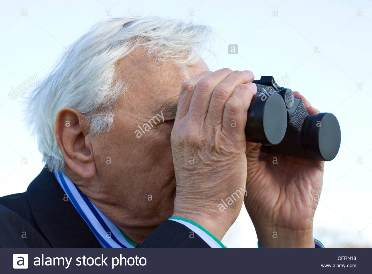 senior-man-looking-through-a-pair-of-binoculars-with-lens-caps-still-CFRN18.jpg