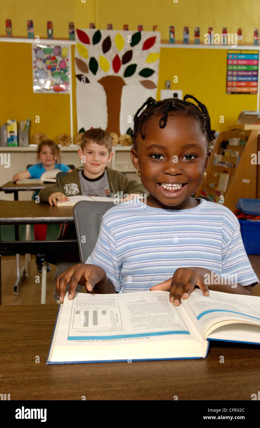 Five Year Old Girl Reading at her Desk in a Classroom Stock Photo Alamy