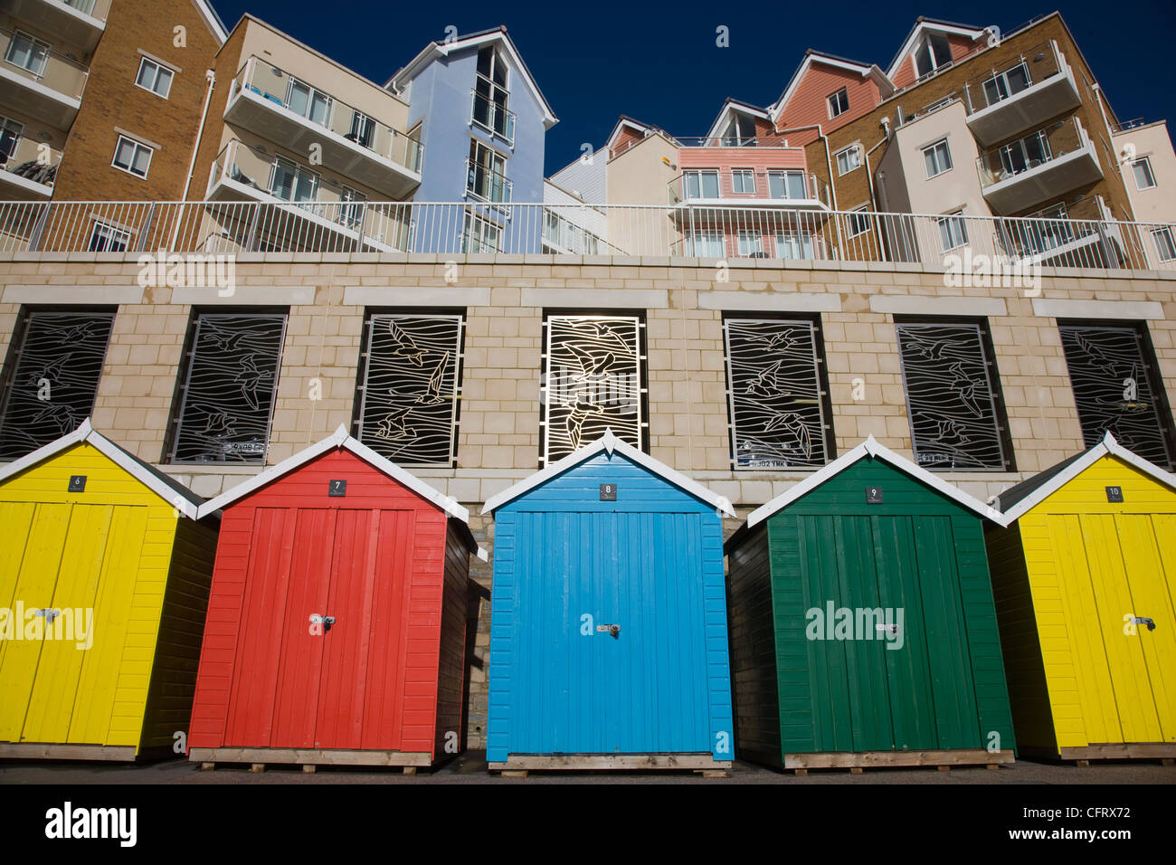 Brightly coloured beach huts and new build flats and apartments along the sea front in