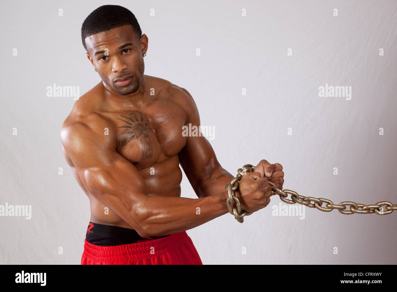 Muscular African American Black man with a heavy chain around his wrists, looking at the camera Stock Photo
