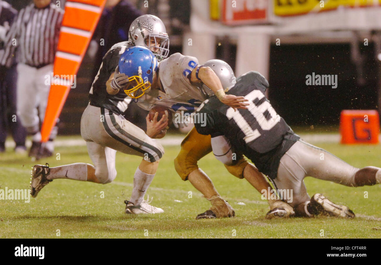 Austin Day (#28) of Foothill High is stopped by (L-R) Zach Moranville and Paul Wright (#16) of De La Salle during their NCS4A championship game at McAfee coliseum in Oakland, Calif. on Saturday, Dec. 9, 2006. (Sherry LaVars/Contra Costa Times) Stock Photo