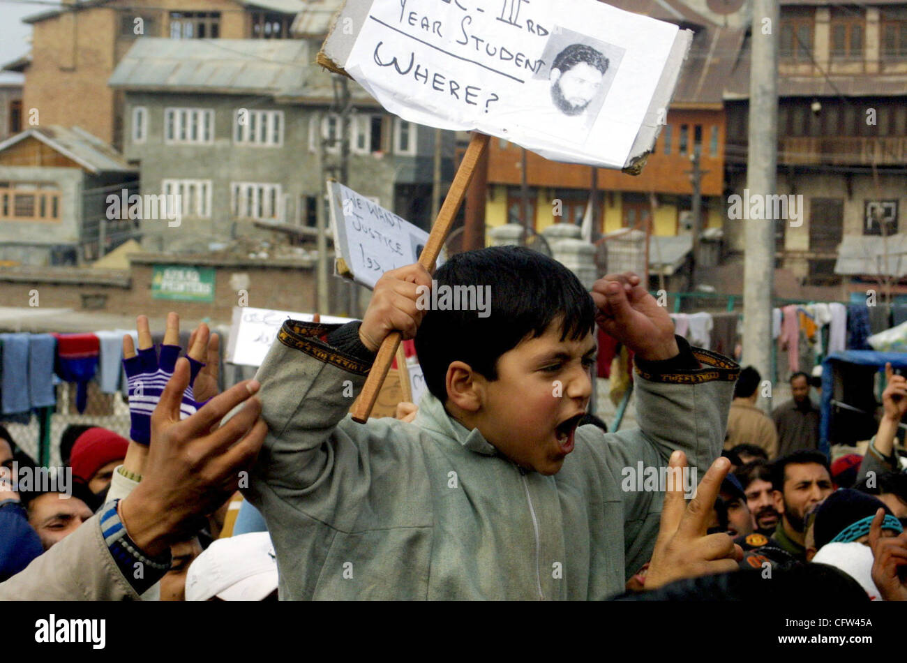 Kashmiri protestors shout slogans as they hold a placard with pictures ...