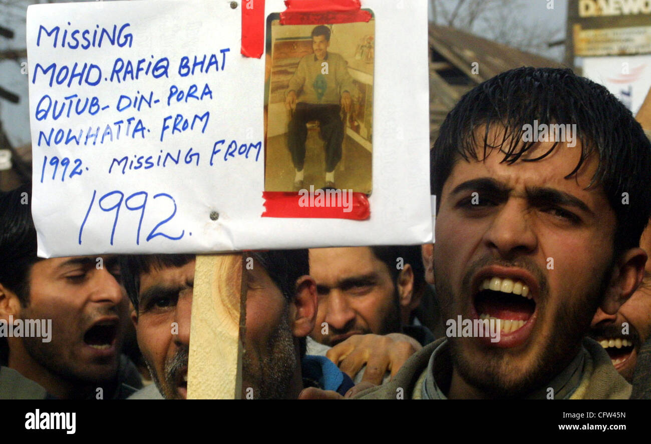 Kashmiri protestors shout slogans as they hold a placard with pictures ...