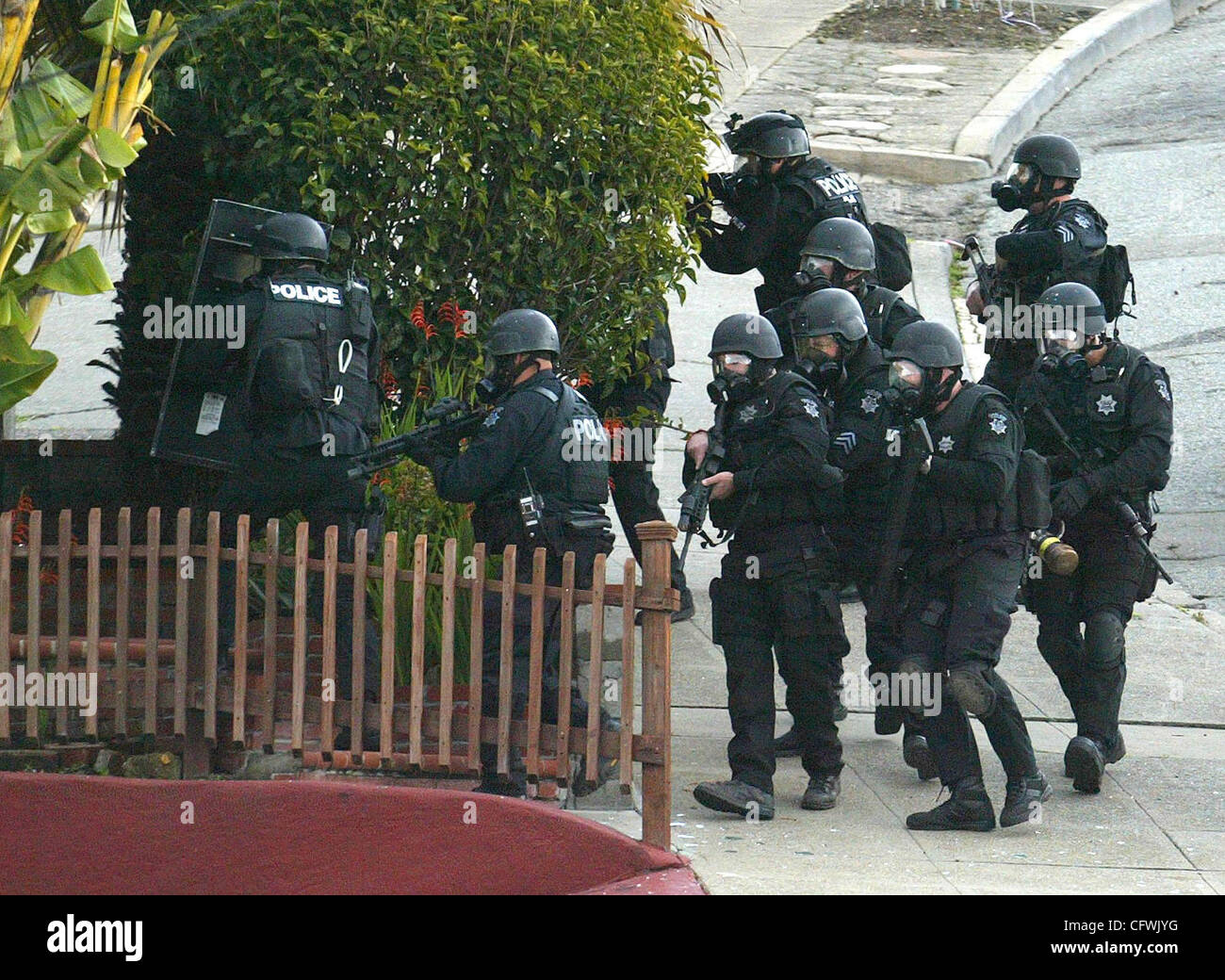Members of the Oakland Police Department, wearing tear gas masks, are about to force the entry after shooting tear gas inside the house where a man barricaded himself early Tuesday Feb, 27, 2007 on the 2800 block of Brookdale in Oakland, Calif. No injuries. (Ray Chavez/The Oakland Tribune) Stock Photo