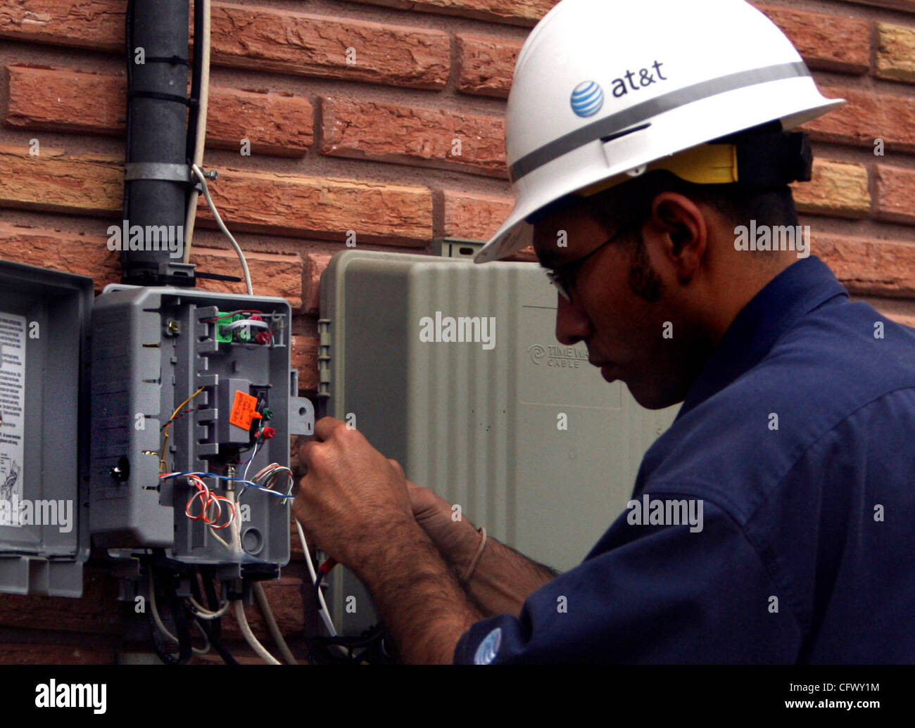BUSINESS -- AT&T technician Vincent Orta connects the Huddleston home ...
