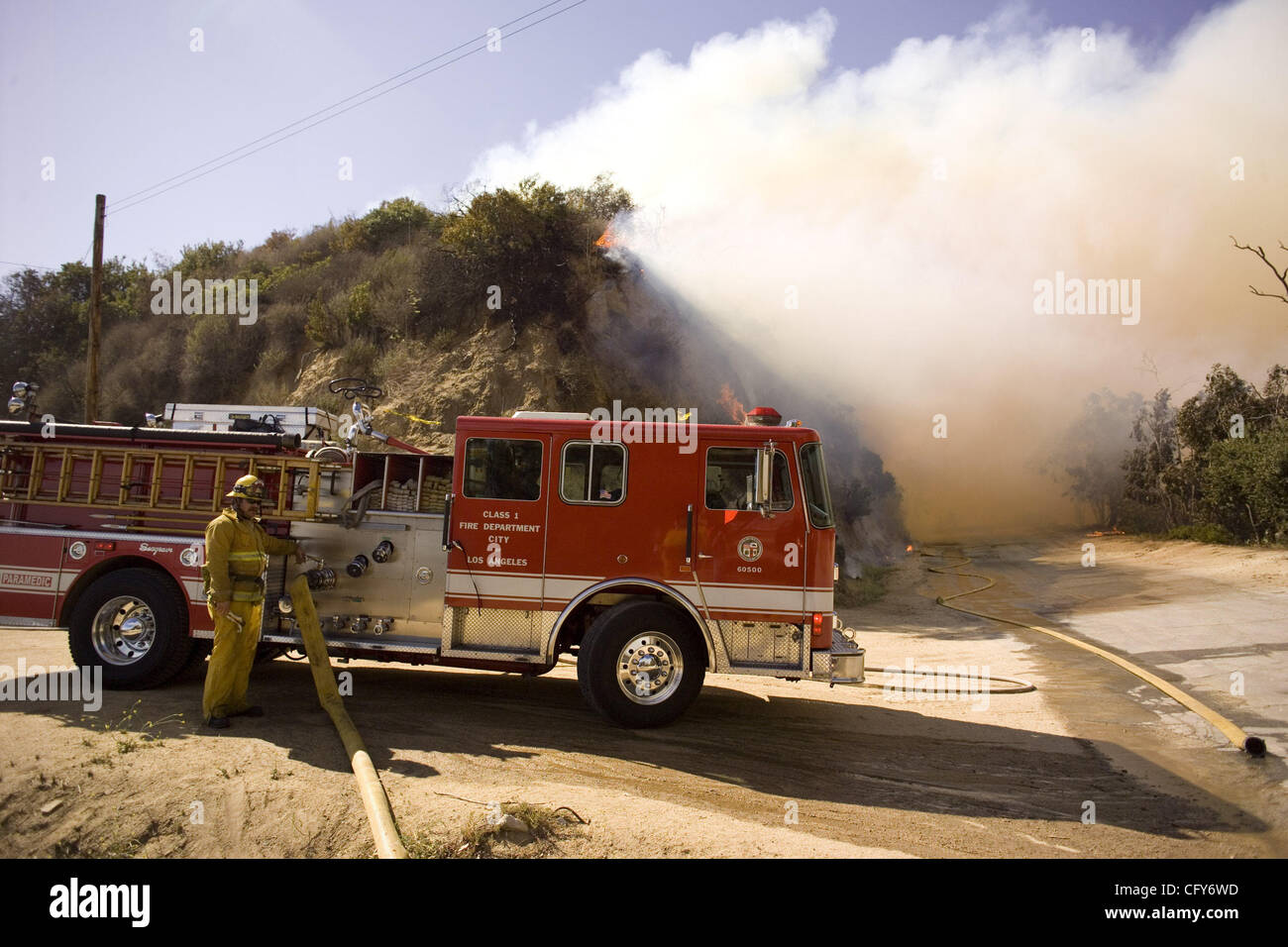 A firefighter fills his truck with water as a brush fire gets out of control in Griffith Park, Los Angeles. Authorities said the fire has scorched 600 acres of trees and brush in Los Angeles' sprawling Griffith Park Tuesday. No homes were immediately threatened, but evacuations were put into effect  Stock Photo