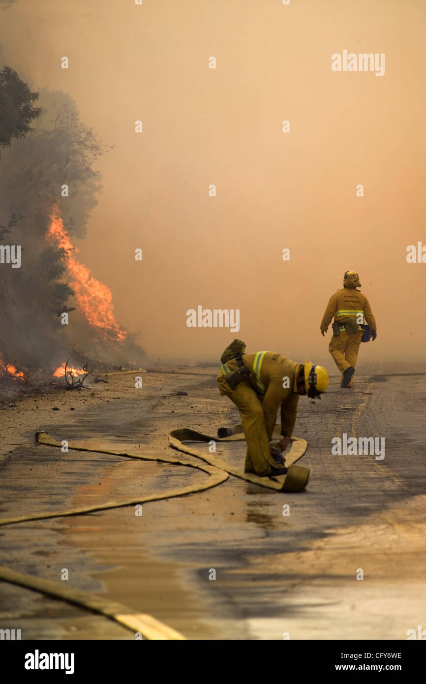 A firefighter retrieves a burnt firehose in the Griffith Park in the Griffith Park, Los Angeles, wild fire. Authorities said the fire has scorched 600 acres of trees and brush in Los Angeles' sprawling Griffith Park Tuesday. No homes were immediately threatened, but evacuations were put into effect  Stock Photo