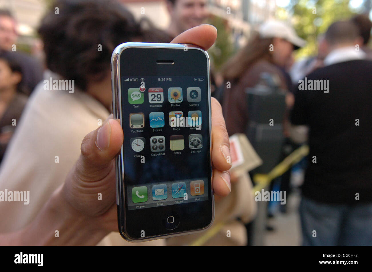 Apple Store employees show off the iPhone to people waiting in line to