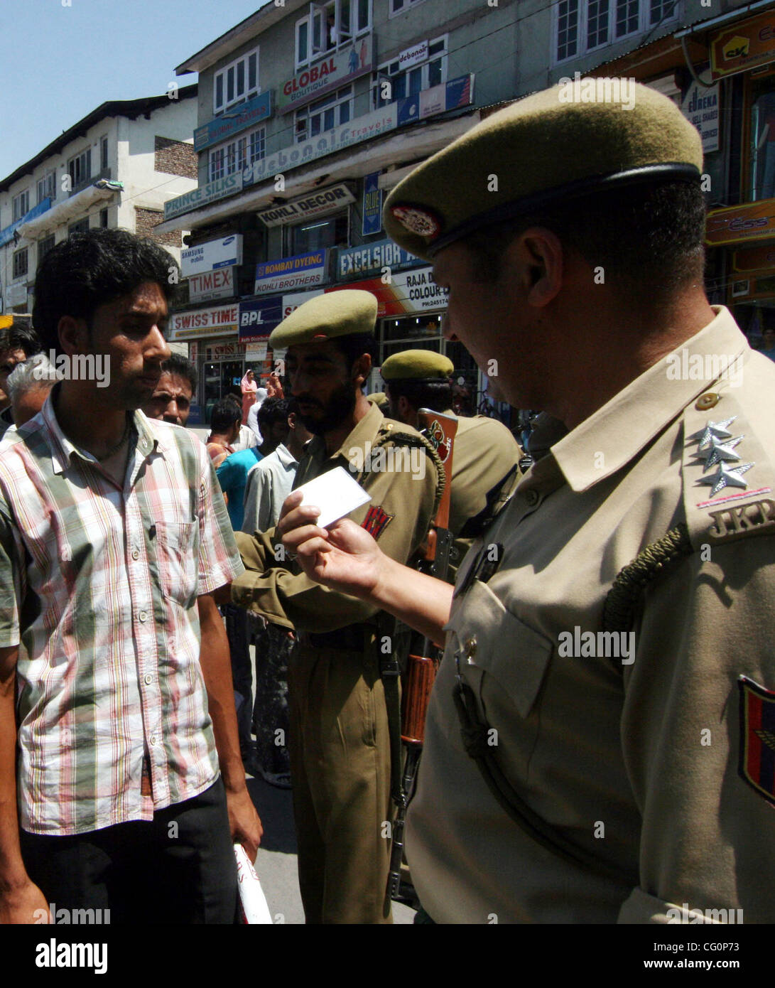 An Indian police officer checks the identity cards of people during a