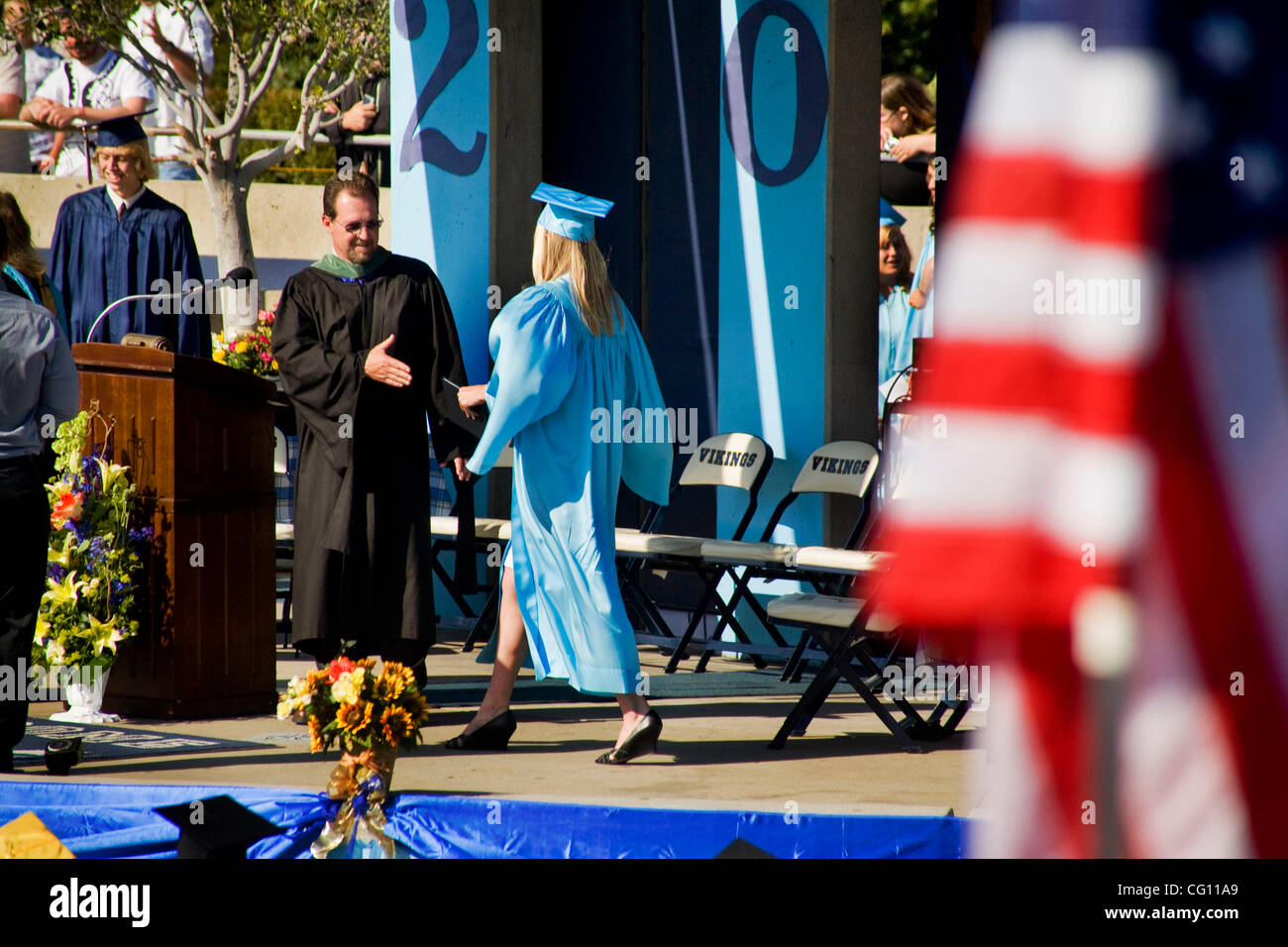Wearing cap and gown and carrying her new diploma, a graduating high ...