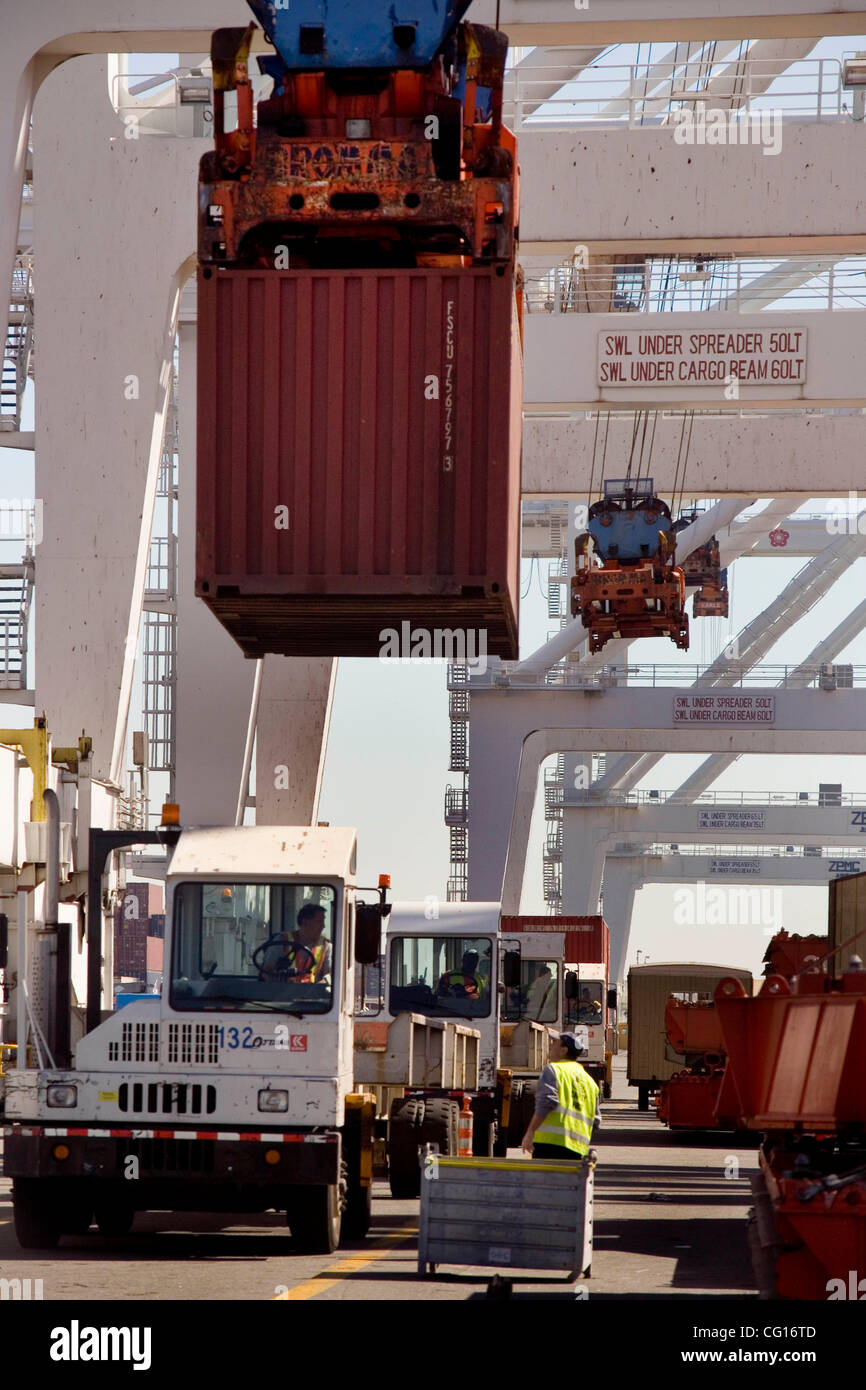 Specialized trucks line up to receive container cargo as it is unloaded ...