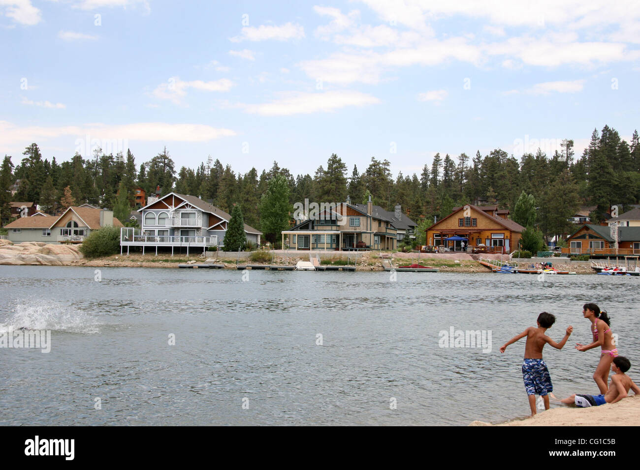 Aug 05, 2007 - Big Bear, CA, USA - Big Bear Lake is located in San Bernardino county and it provides an attractive setting for many outdoor activities, including fishing, boating and water skiing.  Pictured:  Children skip rocks and pebbles across the lake, in the background are some of the lake fro Stock Photo