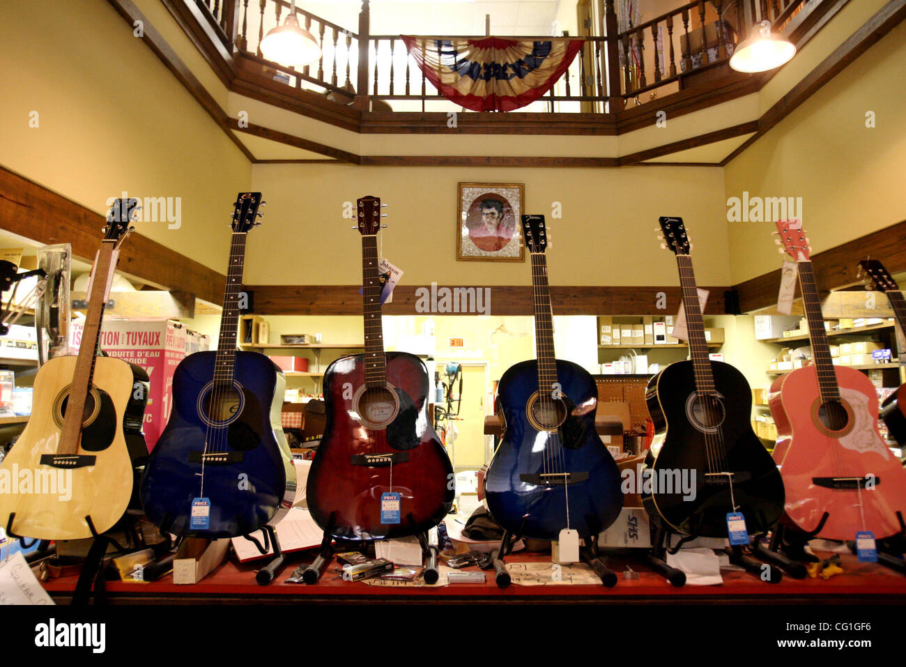 081507 acc elvis 22 Staff Photo by Gary Coronado/The Palm Beach Post 0041321A With Story by Rachel Sauer--Tupelo, Mississippi--A portrait of Elvis Presley hangs above guitars sold amongst hardward supplies at Tupelo Hardware in Tupelo, Mississippi. In 1946, Elvis' mother, Gladys, brought him here to Stock Photo