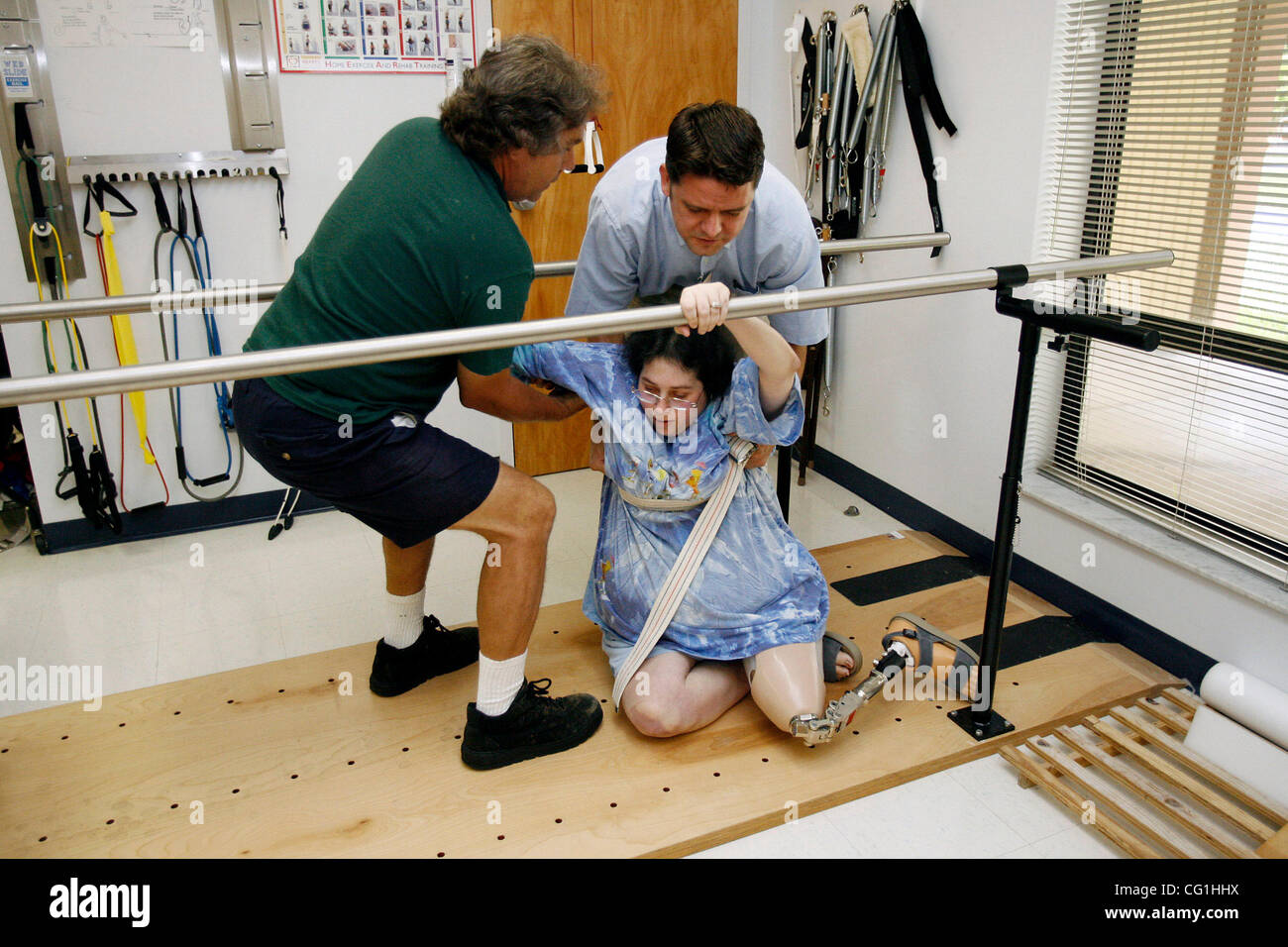 Aug 16, 2007 - Atlantis, FL, USA - Elissa Wehner takes a fall while walking on the parallel bars during a therapy session.  Her therapist Kenneth O' Sullivan (back, right) and her husband, Tom Wehner (left) help her back on her feet.  Elissa Wehner goes to rehabilitative therapy at JFK hospital's ou Stock Photo