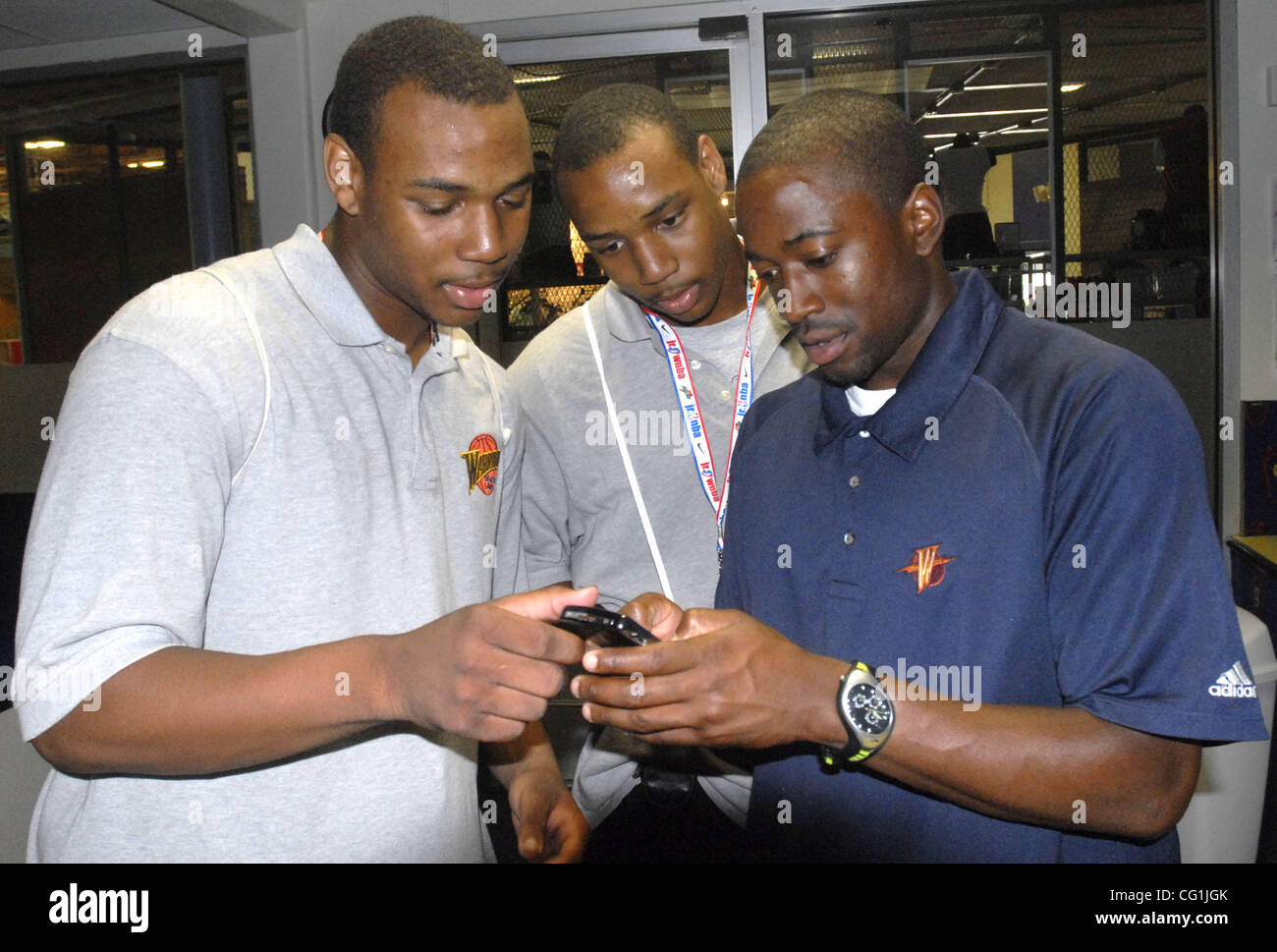 After they refereed a Golden State Warriors youth summer camp basketball game Eighteen year old twin brothers Marseilles Stewart (left) and Dominic Stewart (center) have Warriors Camp Director Justin Bell (right) inter his e-mail address into Marseilles's personal digital assistants device in San Ra Stock Photo