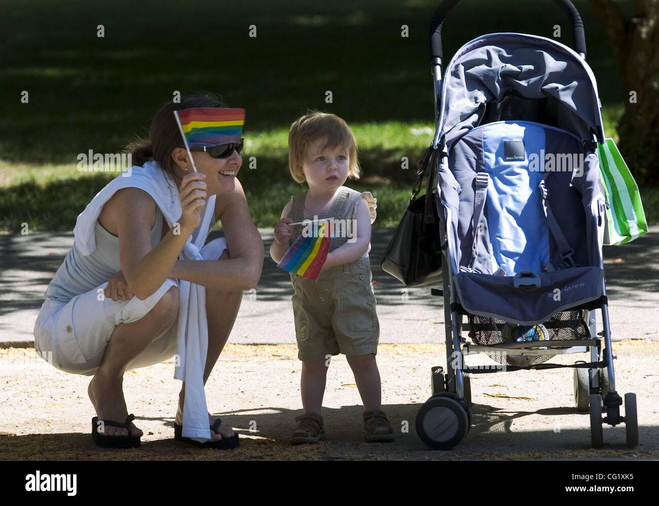 Liz Fenton (cq) and her daughter, Ellie Sutliff (cq), 17 months, wave their rainbow flags from Capitol Park as the gay pride parade passes by Saturday. The Sacramento Bee/  Anne Chadwick Williams/  June 16, 2007 Stock Photo