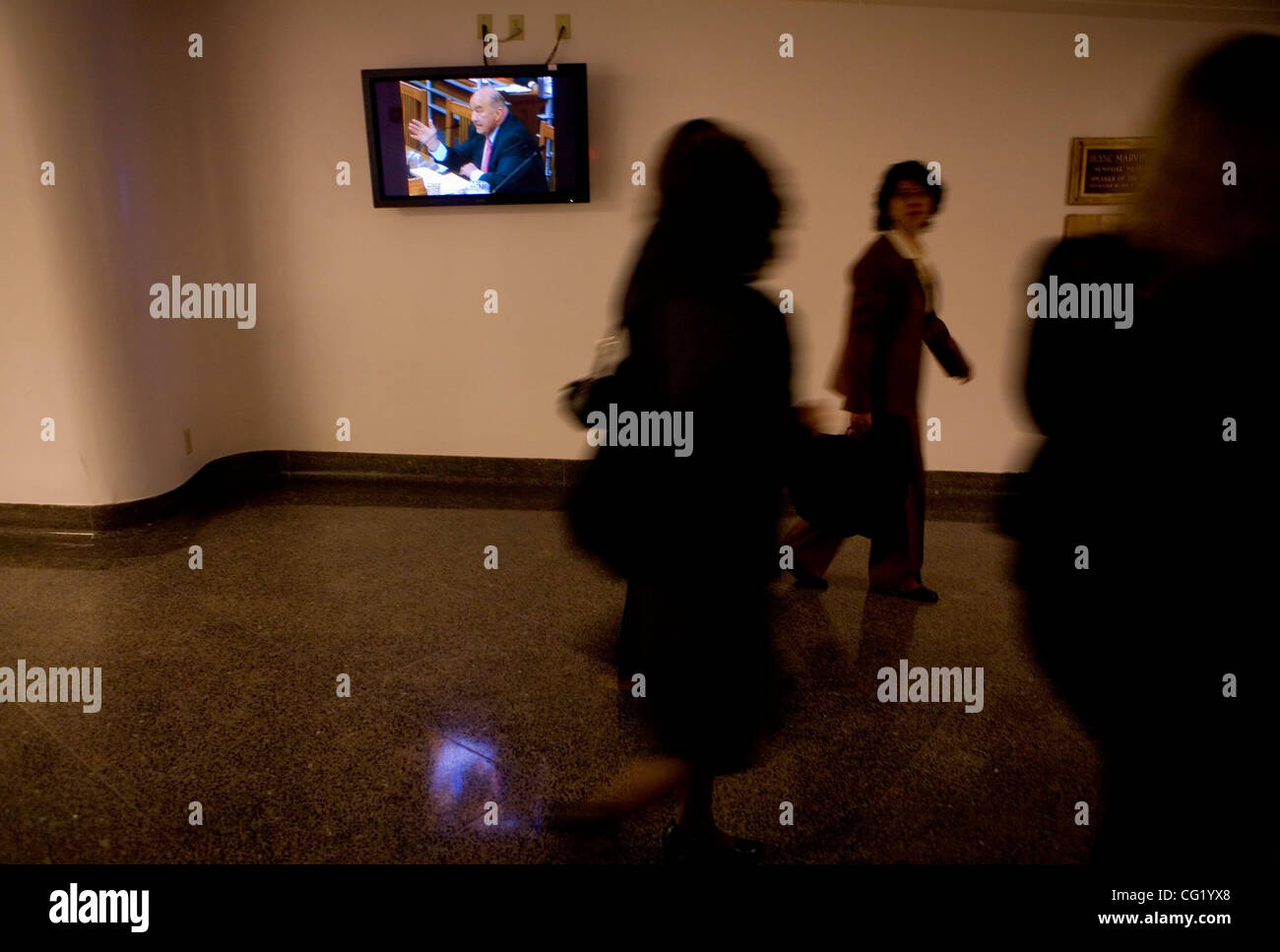 People walk past the television playing the testimony of Charles B ...