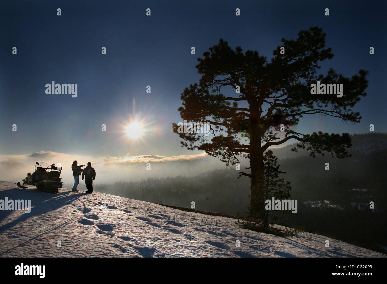 Two snowmobilers take a rest and enjoy the view of Bear Valley during