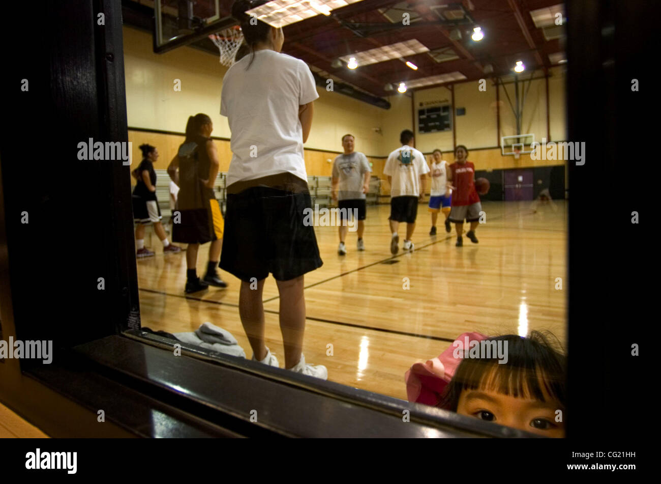 Three-year-old Kimiko Aoki bides her time as her mother, Kelli Aoki, left, coaches the Warlords girls basketball team Wednesday, March 14, 2007 at the Sacramento Asian Sports Foundation's newly completed gymnasium. After more than a decade of planning and construction, the gym/ community center open Stock Photo