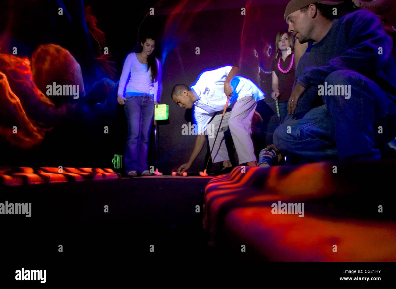 Danny Gumbs (cq), center, tees up at the Adventure Zone's Mineshaft mini golf course Thursday, April 12, 2007 in Carmichael. The indoor nine hole course is lit by black lights and sports a series of neon murals depicting prehistoric creatures.  The Sacramento Bee /  Carl Costas Stock Photo