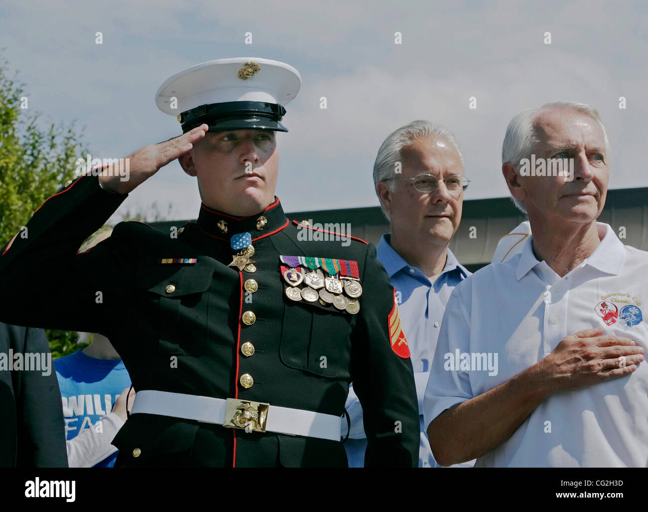 Local Medal of Honor recipient Marine Corps Reserve Sergeant DAKOTA MEYER (left) stands at attention saluting alongside state Senate President DAVID WILLIAMS (center) and Governor STEVE BESHEAR as the national anthem is played during a parade opening the 38th annual Cow Days festival. The event was  Stock Photo