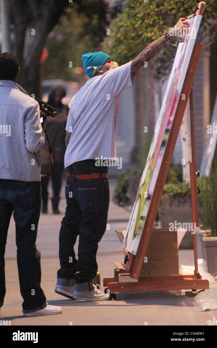 Chris Brown makes a painting mural using spraypaint outside a studio