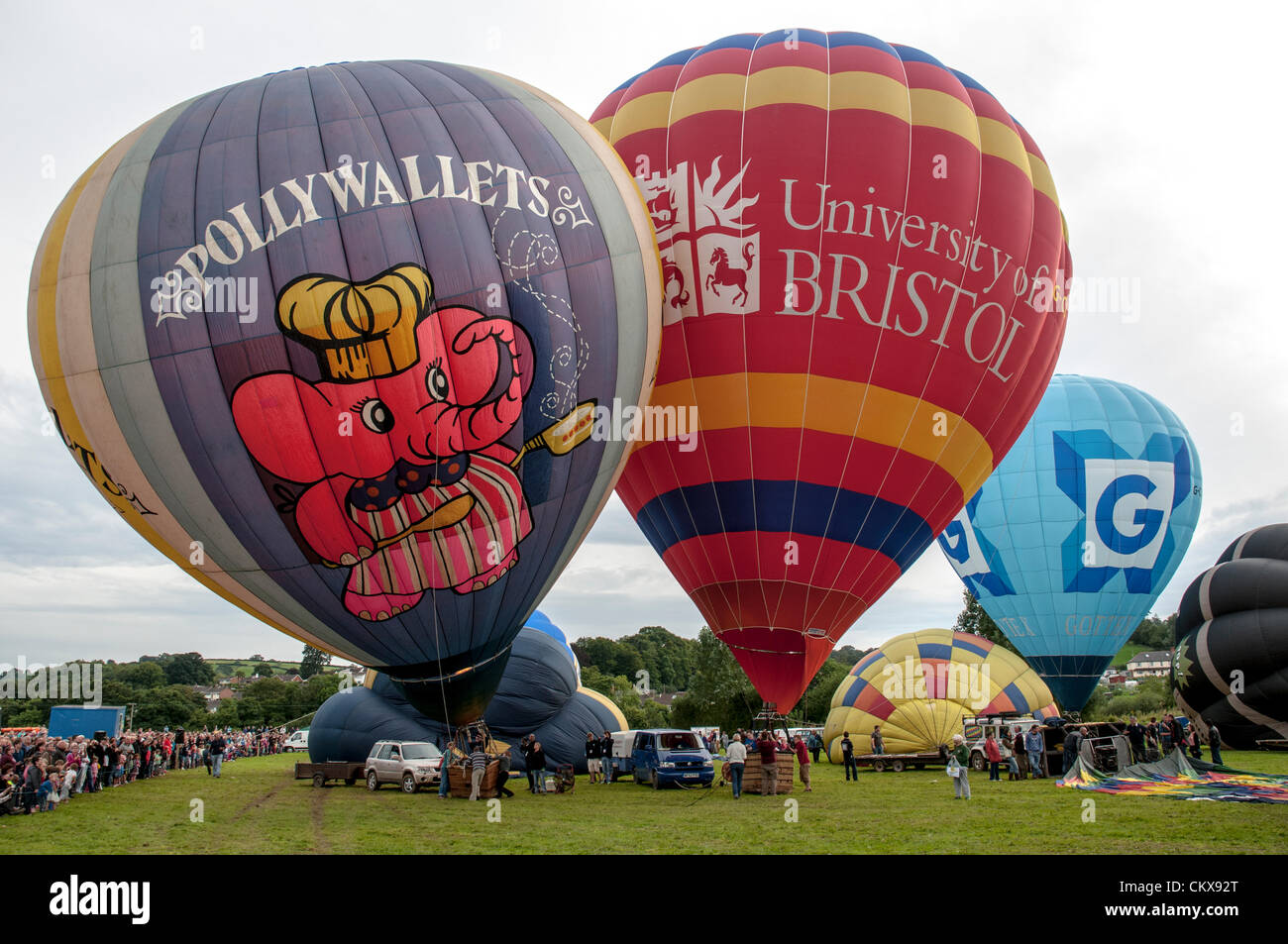 26th Aug 2012. The G-POLY, 1978 CAMERON N-77 Pollywallets ballon Cameron-Z Series (UK) (Gottex) (Z-90) (G-CCNN) balloon and the John Harris (G-CDWD)  University of Bristol balloon is prepared for launch at the Tiverton balloon festival in Tiverton, Devon, UK. Stock Photo