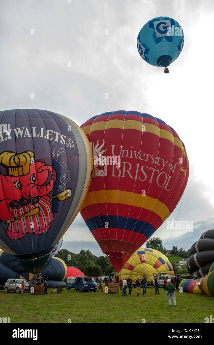 26th Aug 2012. The G-POLY, 1978 CAMERON N-77 Pollywallets ballon Cameron-Z Series (UK) (Gottex) (Z-90) (G-CCNN) balloon and the John Harris (G-CDWD)  University of Bristol balloon is prepared for launch at the Tiverton balloon festival in Tiverton, Devon, UK. Stock Photo