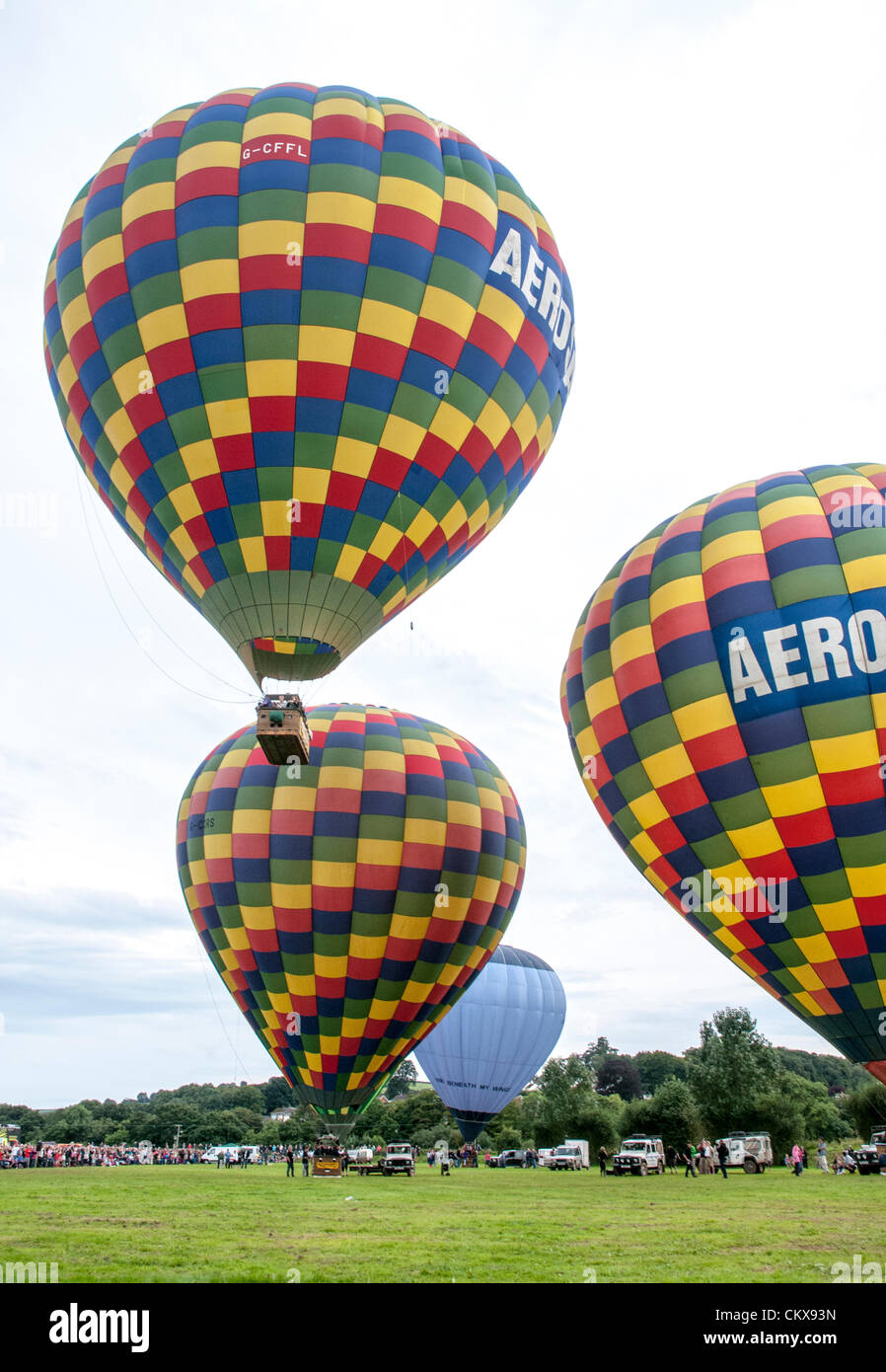 26th Aug 2012. The the Colin Hodges G-CFFL Lindstrand LBL-317A Aerosaurus balloon takes off between the G-CCRS - Lindstrand Aerosaurus balloon and the G-CDHN Lindstrand LBL-317A Aerosaurus balloon at the Tiverton balloon festival in Tiverton, Devon, UK. Stock Photo