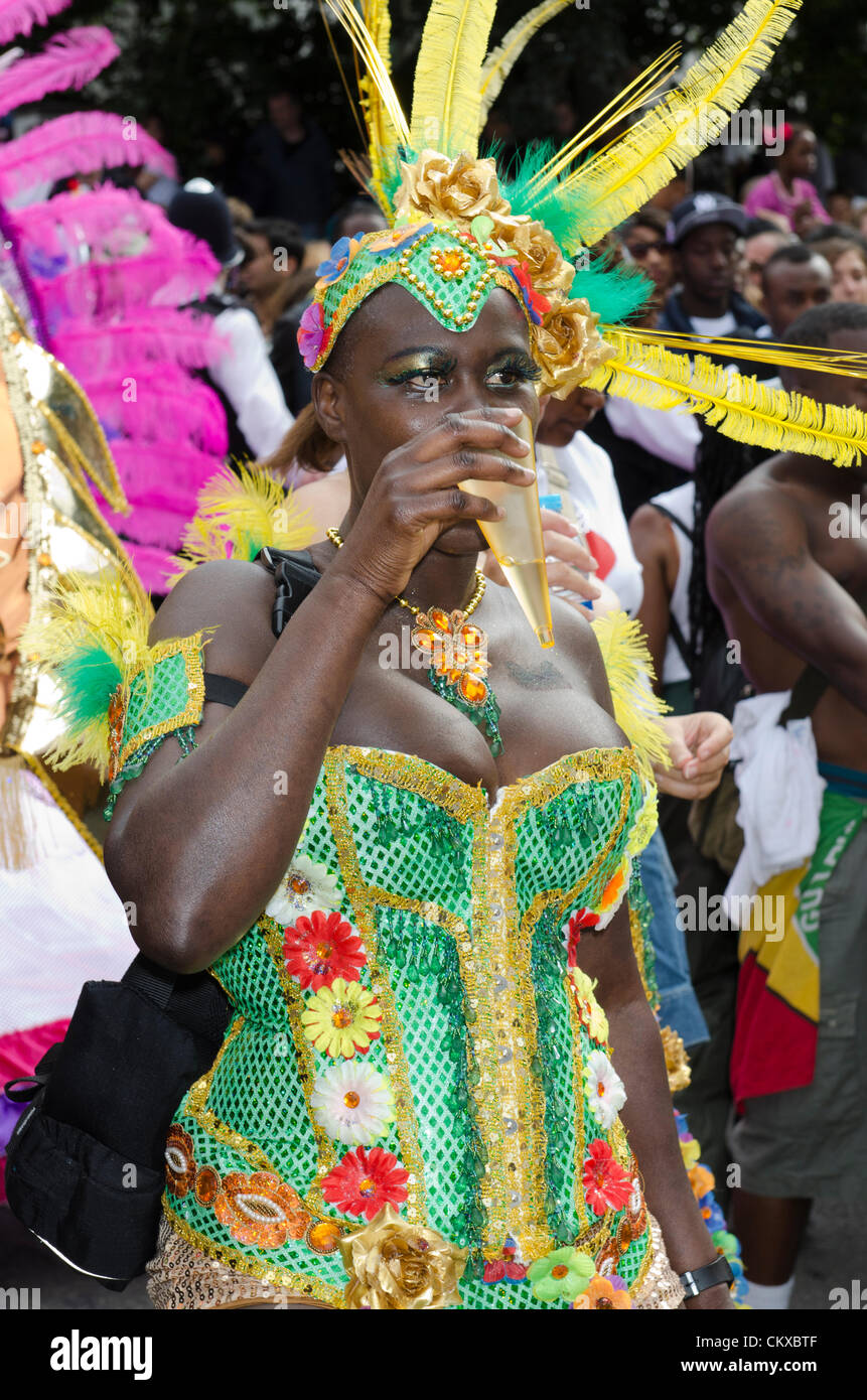 woman masquerader takes a drink in carnival costume, Notting Hill Carnival Bank holiday Monday , London UK 27th August 2012 Stock Photo