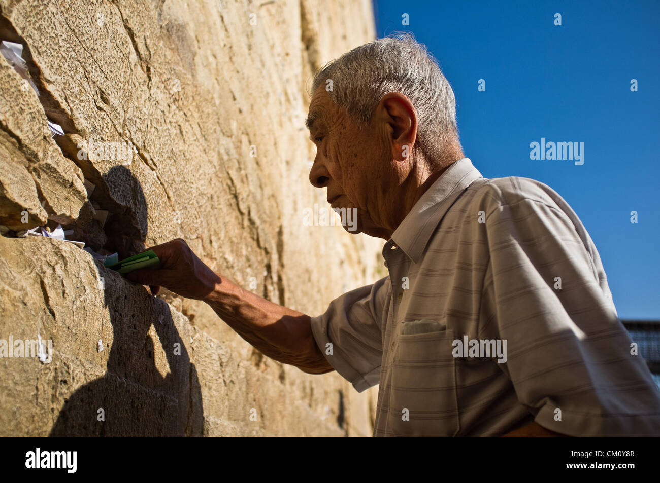 Miyake Nobuo, 83, survivor of Hiroshima at age 16, 2Km from the hypocenter, places a prayer for nuclear abolition in the crevices between the stones of the western Wall. Jerusalem, Israel. 10-September-2012.   Hibakusha, survivors of the August 6th, 1945 bombing of Hiroshima, visit Israel to promote nuclear abolition. Calling “No More Hiroshimas, No More Nagasakis!” they place their prayers between the Kotel stones. Stock Photo