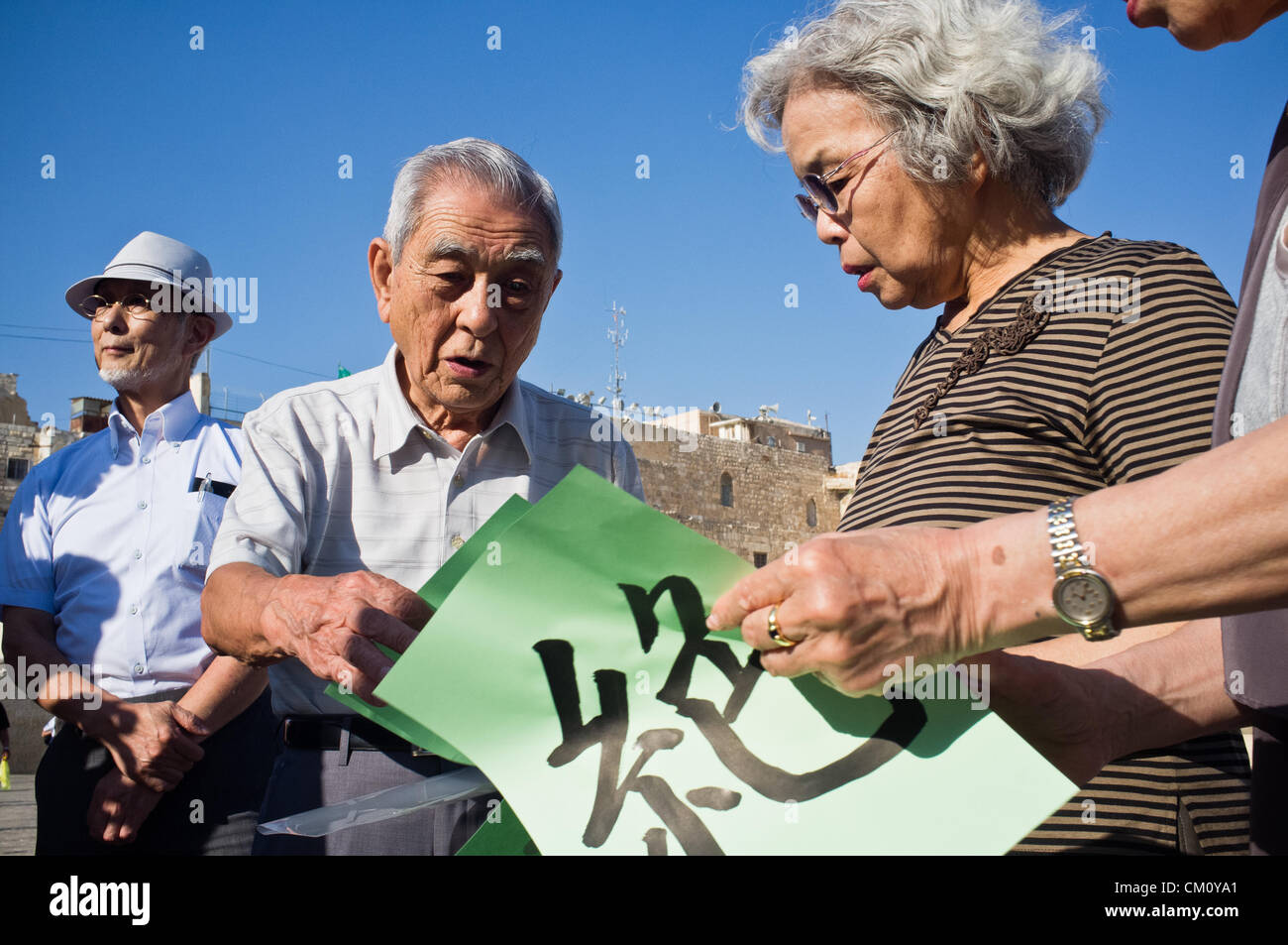 Hibakusha, Hiroshima children survivors, prepare three pages of kanji that together comprise “nuclear abolition” at the Western Wall. Jerusalem, Israel. 10-September-2012.   Hibakusha, survivors of the August 6th, 1945 bombing of Hiroshima, visit Israel to promote  nuclear abolition. Calling “No More Hiroshimas, No More Nagasakis!” they place their prayers between the Kotel stones. Stock Photo